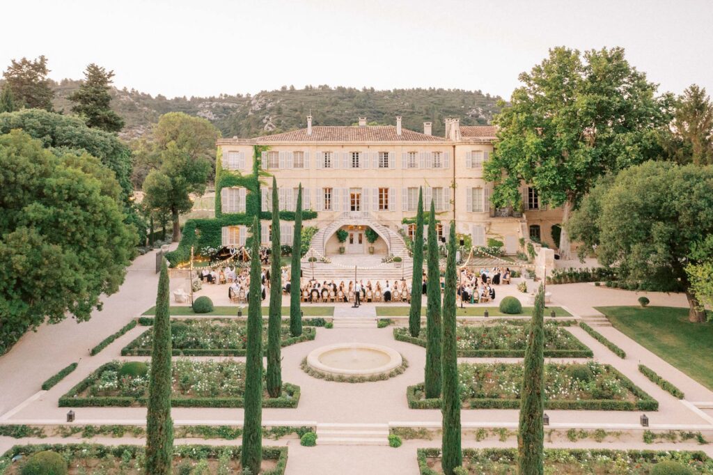 Symmetrical view of a Château d'Estoublon, a wedding venue in the South of France featuring manicured gardens, fountains, and elegant alfresco reception seating.